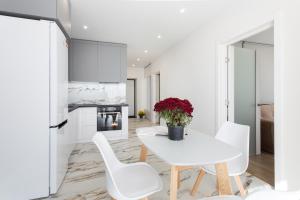 a white kitchen with a white table and white chairs at Complex Rogatinskiy in Kharkiv