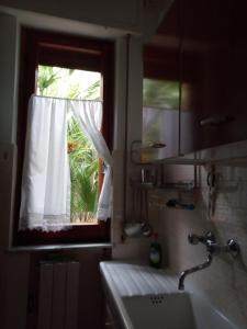 baño con lavabo y ventana con cortina en Home Caviglia CITRA 09029-LT-0618, en Finale Ligure