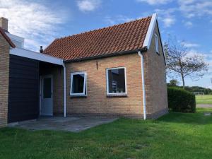 una pequeña casa de ladrillo con techo rojo en De Vrije wil en Buren
