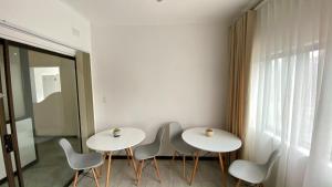 2 Tische und Stühle in einem Zimmer mit Fenster in der Unterkunft Villa Portia in Johannesburg