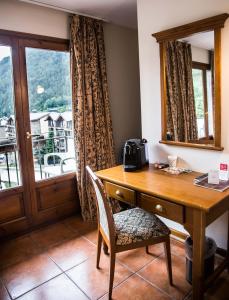 a wooden desk with a chair next to a window at Hotel Xalet Verdú in Arinsal