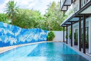 a swimming pool in a house with a blue tile fence at Anona Beachfront Phuket Resort-SHA EXTRA PLUS in Patong Beach