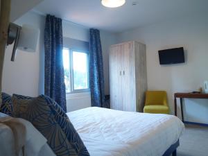 a bedroom with a bed and a chair and a window at Hôtel Restaurant Le Sainte Marguerite in Pornichet
