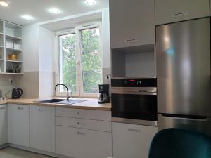 a kitchen with white cabinets and a stainless steel refrigerator at Apartament Stok o krok in Stronie Śląskie