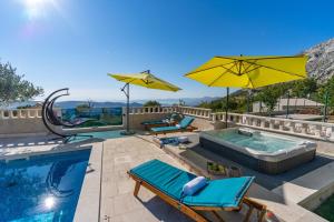 een zwembad met stoelen en parasols en een zwembad bij Villa Runje in Žrnovnica