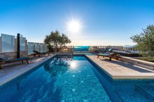 een zwembad met banken bovenop een gebouw bij Villa Runje in Žrnovnica