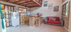 a kitchen with a couch and a refrigerator at Cantim da Flor - Vale do Capão in Vale do Capao