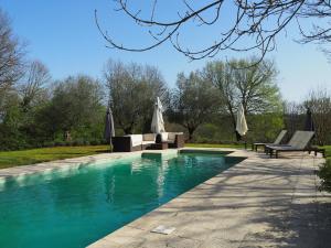 una piscina con sillas y sombrillas en un parque en Vue sur Gindou gîte, en Gindou