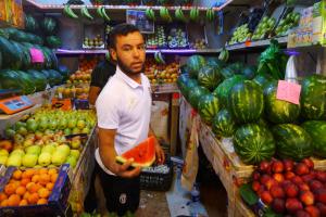a man holding a slice of watermelon in a market at Zahara de Los Atunes Beachhouse in Zahara de los Atunes