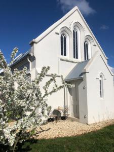 a white church with a tree in front of it at St James Converted Church in Miners Rest