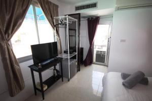 una camera con letto, televisore e finestra di Hua Hin Paradise Guesthouse a Hua Hin