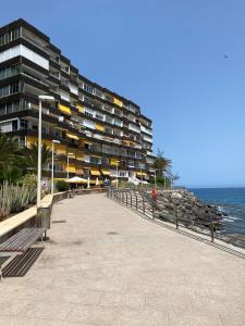 - un grand bâtiment à côté d'une plage avec bancs dans l'établissement Exclusives Apartment 10 meters to Ocean, à Maspalomas