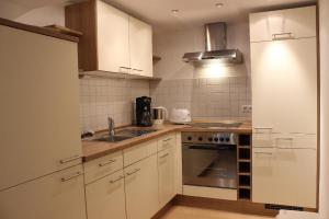 a kitchen with white cabinets and a sink and a stove at Wohlfühl-Ferienwohnung Sonja in Bodenmais