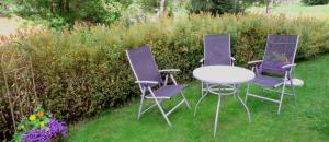 tres sillas púrpuras y una mesa en el césped en Wohlfühl-Ferienwohnung Sonja, en Bodenmais