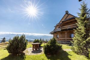 ein Blockhaus mit einer Bank davor in der Unterkunft udanypobyt Dom Hillside in Gliczarów Górny