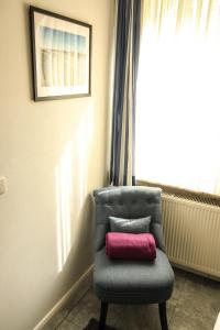 a chair with a pink pillow sitting next to a window at Kapitaenshaus-Lassen-Zimmer-Bounty in Westerland (Sylt)