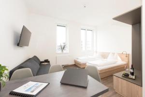 a white living room with a laptop on a table at TT-ROOMS - kontaktlos mit Self Check-in in Graz