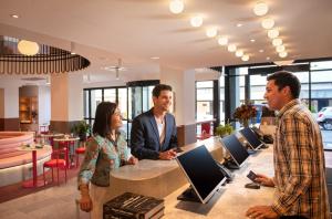 a group of people standing around a counter with computers at Hotel Indigo Adelaide Markets by IHG in Adelaide +85 photos