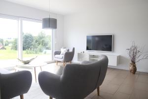 sala de estar con sillas y TV en la pared en Auszeit mit Weitblick in der Sächsischen Schweiz - kleiner Bauernhof mit Tieren und Wallbox en Rathmannsdorf