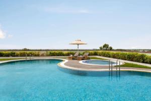 una piscina con sombrilla, mesa y sillas en Ramada by Wyndham Aligarh GT Road, en Aligarh