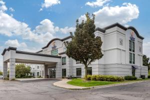 een wit gebouw met een boom ervoor bij Comfort Inn & Suites in Grand Blanc