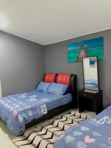 una camera con due letti e un dipinto sul muro di Aina Guest House a Kota Bharu