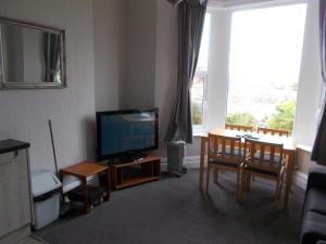 a living room with a television and a table and chairs at Kelso House holiday flats in Blackpool