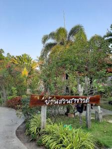 un panneau en bois dans un parc planté d'arbres et de buissons dans l'établissement Bansuanrachawadee B&b, à Si Saket