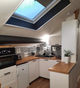 eine Küche mit weißen Schränken und einem Dachfenster in der Unterkunft Superbe appartement pour 2, au cœur de l'Ariège! in Ussat