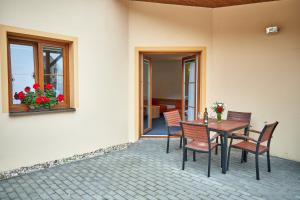 eine Terrasse mit einem Tisch, Stühlen und einem Fenster in der Unterkunft Penzion Volařík in Dolní Dunajovice