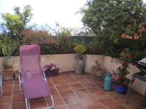 une chaise rose assise sur une terrasse ornée de plantes dans l'établissement Chambre hôtes Wagram, à Ajaccio