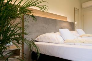 uma cama com lençóis brancos e almofadas ao lado de uma planta em Motel Lohwasser em Lichtenau