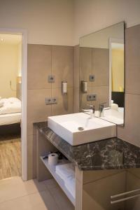 a bathroom with a sink and a mirror and a bed at Motel Lohwasser in Lichtenau