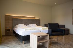 a bedroom with a bed and a chair and a table at Motel Lohwasser in Lichtenau