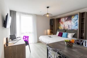 Habitación de hotel con cama y mesa con ordenador portátil en Appart-Hôtel Mer & Golf City Bordeaux Lac, en Burdeos