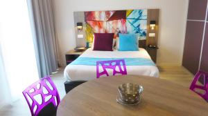 Una habitación de hotel con una cama, una mesa y sillas. en Appart-Hôtel Mer & Golf City Bordeaux Lac, en Burdeos