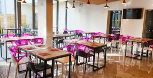 una fila de mesas y sillas en una habitación con sillas rosas en Appart-Hôtel Mer & Golf City Bordeaux Lac, en Burdeos