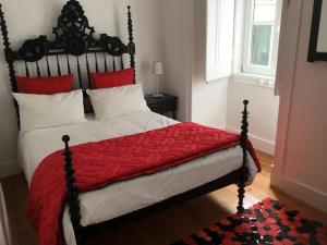 um quarto com uma cama grande e um edredão vermelho em Palacette da Mouraria em Lisboa