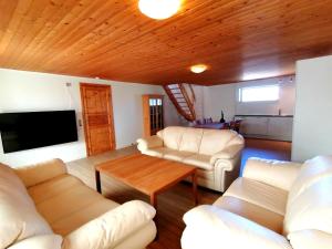 una sala de estar con muebles blancos y techo de madera. en Skovly FerieCenter en Humble
