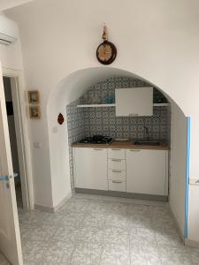 uma cozinha com armários brancos e um relógio na parede em CASA ICARO em Amalfi