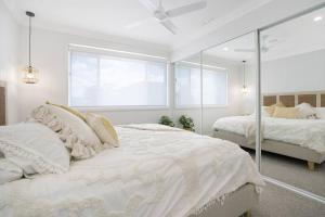 a white bedroom with two beds and a window at Entire Residential Home - Lake Illawarra And Beachside Home Sleeps 12 in Lake Illawarra +36 photos