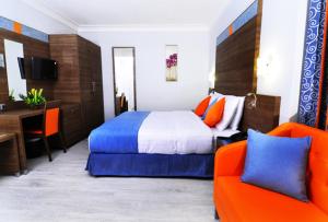 1 dormitorio con 1 cama y 2 sillas de color naranja en Benin Royal Hotel, en Cotonou