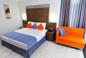 een slaapkamer met een bed en een oranje stoel bij Benin Royal Hotel in Cotonou