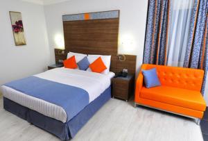 1 dormitorio con 1 cama y 1 silla naranja en Benin Royal Hotel, en Cotonou