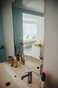 lustro w łazience z umywalką i łóżkiem w obiekcie Villa Balaou - Vue mer exceptionnelle - w mieście Urville-Nacqueville