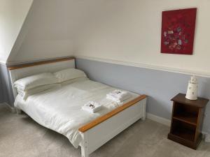 a bedroom with a white bed with a wooden frame at The Eliot Arms in Saint Germans