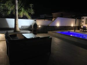 a bottle of wine sitting on a table next to a swimming pool at night at Stunning Villa Arabella - Heated Pool - BBQ - Amazing Terrace - Playa Blanca in Playa Blanca