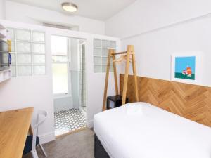 1 dormitorio con cama, escritorio y ventana en The Broadmead en Falmouth