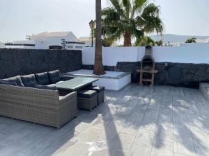a patio with a couch and a table and a palm tree at Stunning Villa Arabella - Heated Pool - BBQ - Amazing Terrace - Playa Blanca in Playa Blanca