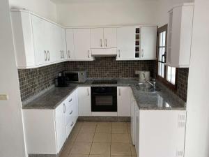 a white kitchen with white cabinets and appliances at Stunning Villa Arabella - Heated Pool - BBQ - Amazing Terrace - Playa Blanca in Playa Blanca